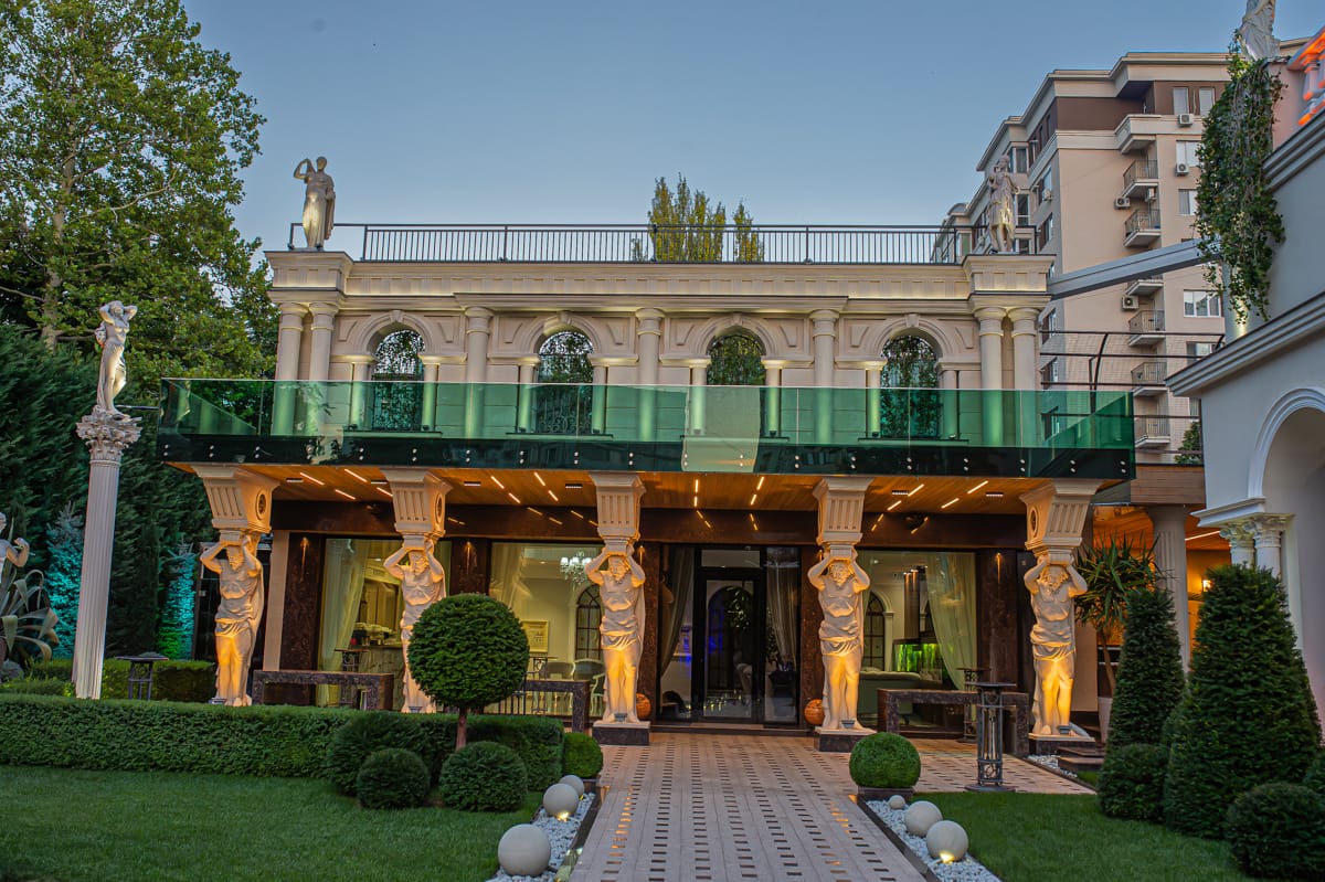 Fațada clasică MiaDora cu cariatide, coloane și balcon de sticlă, la apus